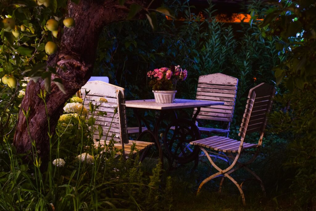 hinter einem Obstbaum, ein Gartentisch und 4 Stühle mit pflanzen
