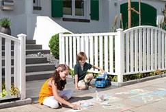 spielende Kinder im Vorgarten vor einem weißen Kunststoffzaun von Traumgarten