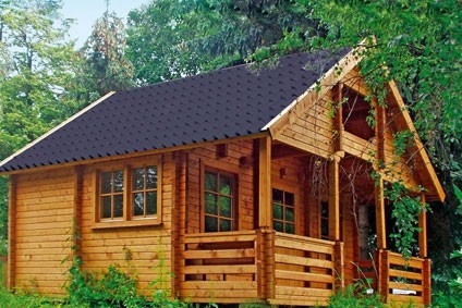 braunes Blockbohlenhaus aus Holz im Wald mit grauer Dacheindeckung